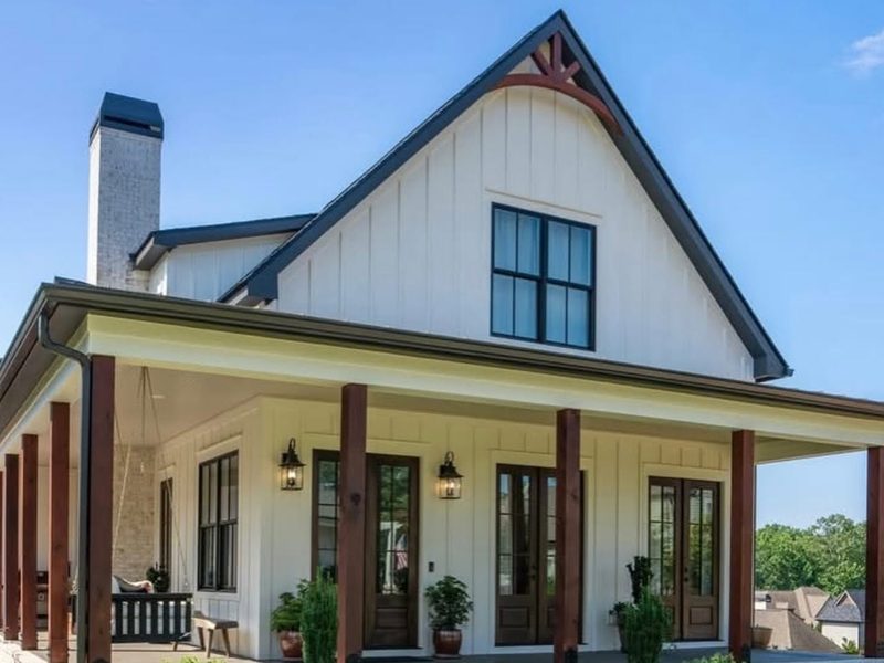 White board and batten home with a wraparound porch and cedar posts